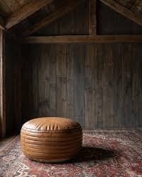 Cognac leather drum pouf on a vintage rug in a timber barn