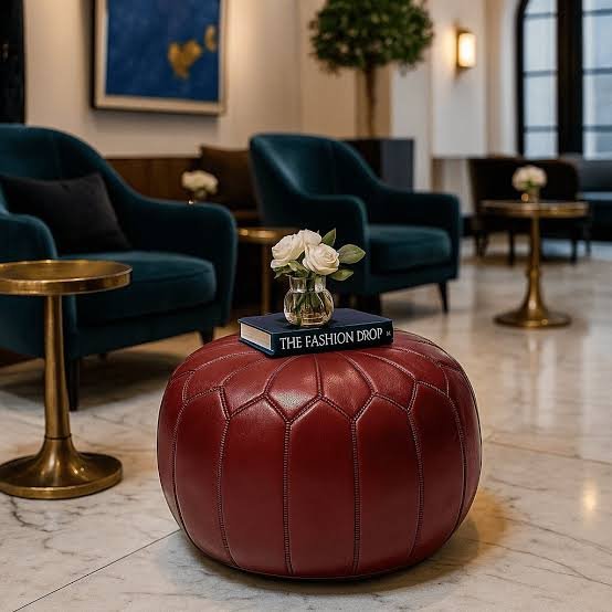 Oxblood leather pouf with paneled stitching in a hotel lounge